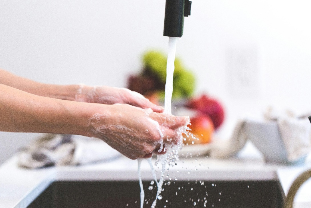 A person washing hands in the kitchen