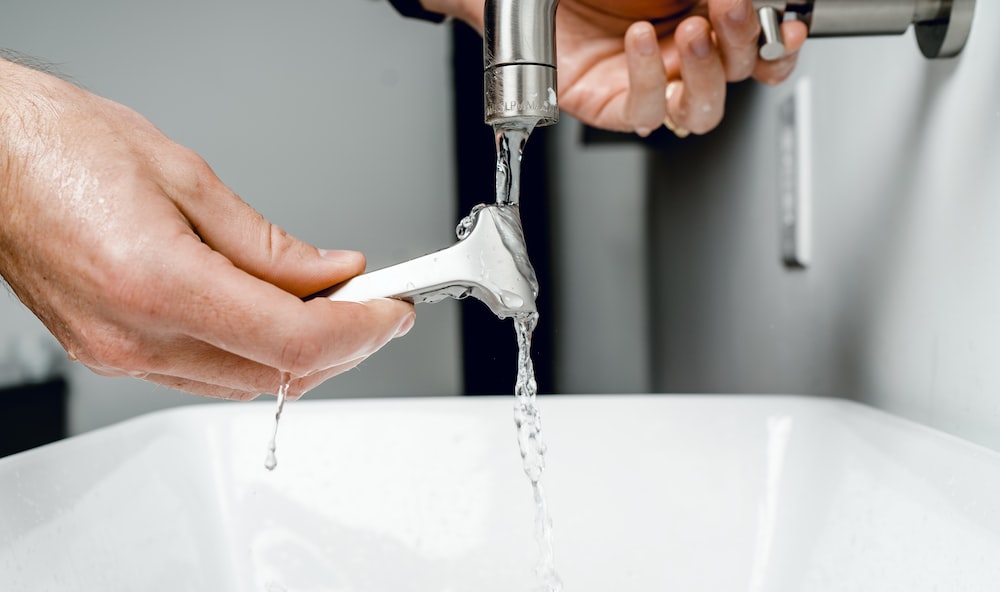 A person washing a razor with tap water