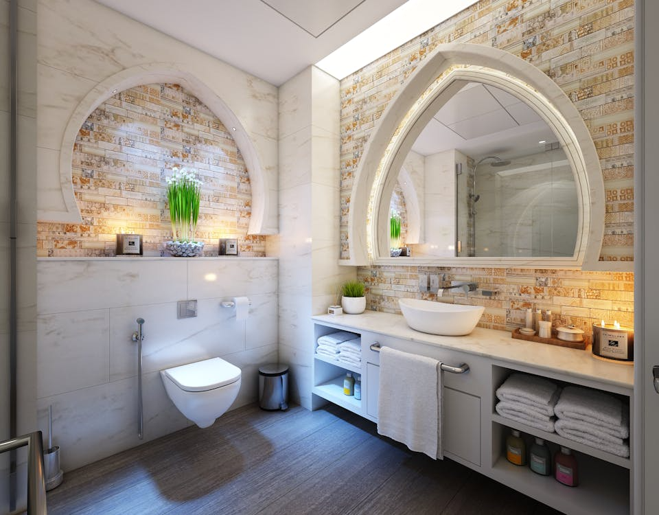 This image shows a luxurious, well-lit bathroom with arched decorative niches, a large mirror, modern fixtures, and elegant stone tile accents.