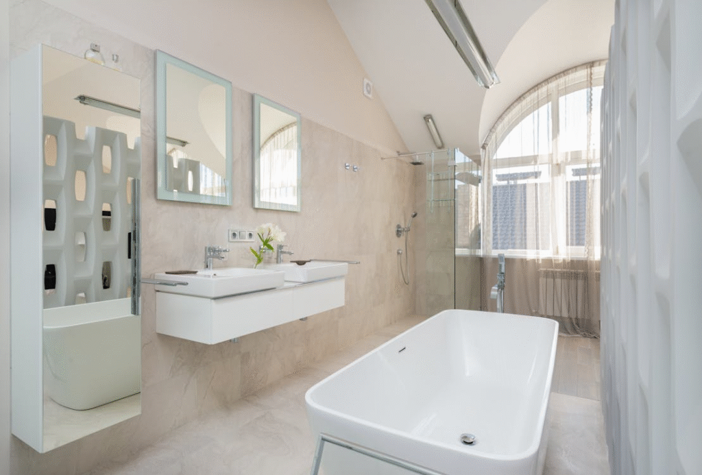 This is a modern, minimalistic bathroom with a freestanding bathtub, double sinks, and a walk-in shower, featuring natural light through large windows.