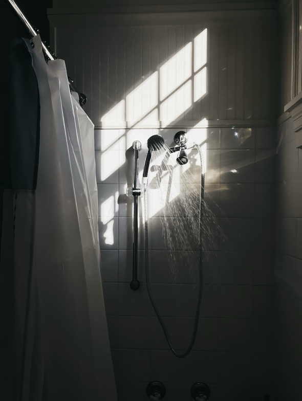 Photo of a stainless steel shower head on a shower stall