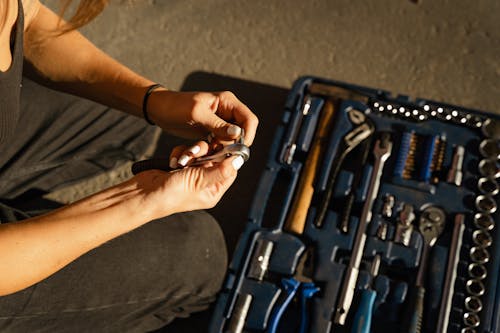 A person holding a steel tool and bolt
