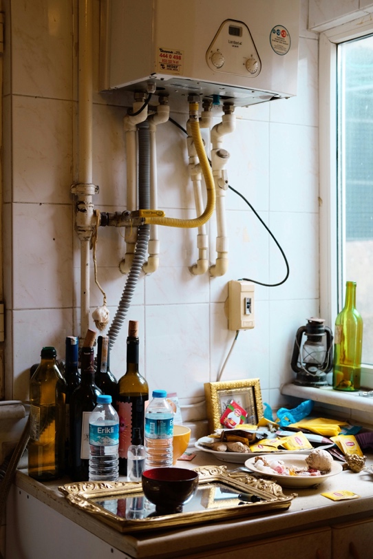 A messy kitchen with a water heater in the background