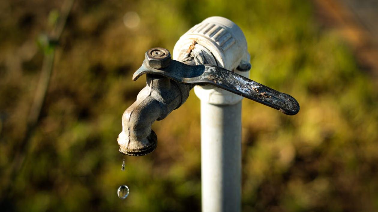 Frozen outdoor water tap dripping in a snowy winter setting.